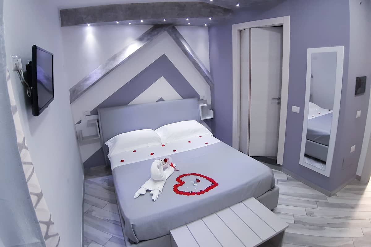 A modern bedroom with a bed, a TV, and a wardrobe.