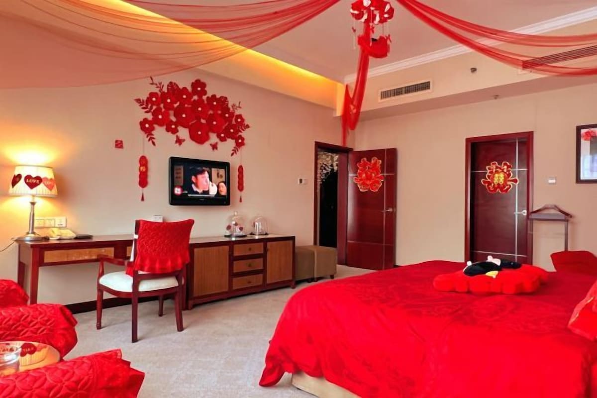 Un dormitorio con temática roja, que incluye una cama, un escritorio y una silla.