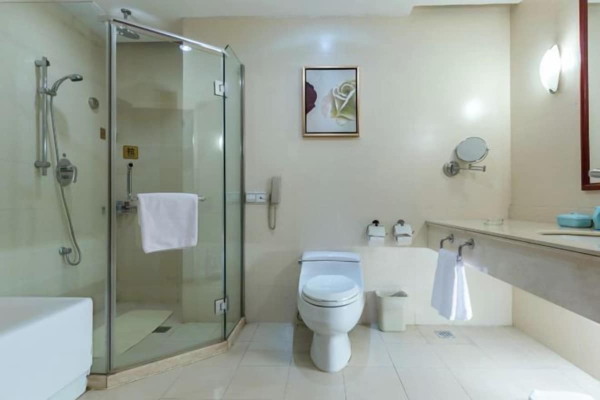 Un baño moderno con ducha de vidrio, inodoro y lavabo con espejo.