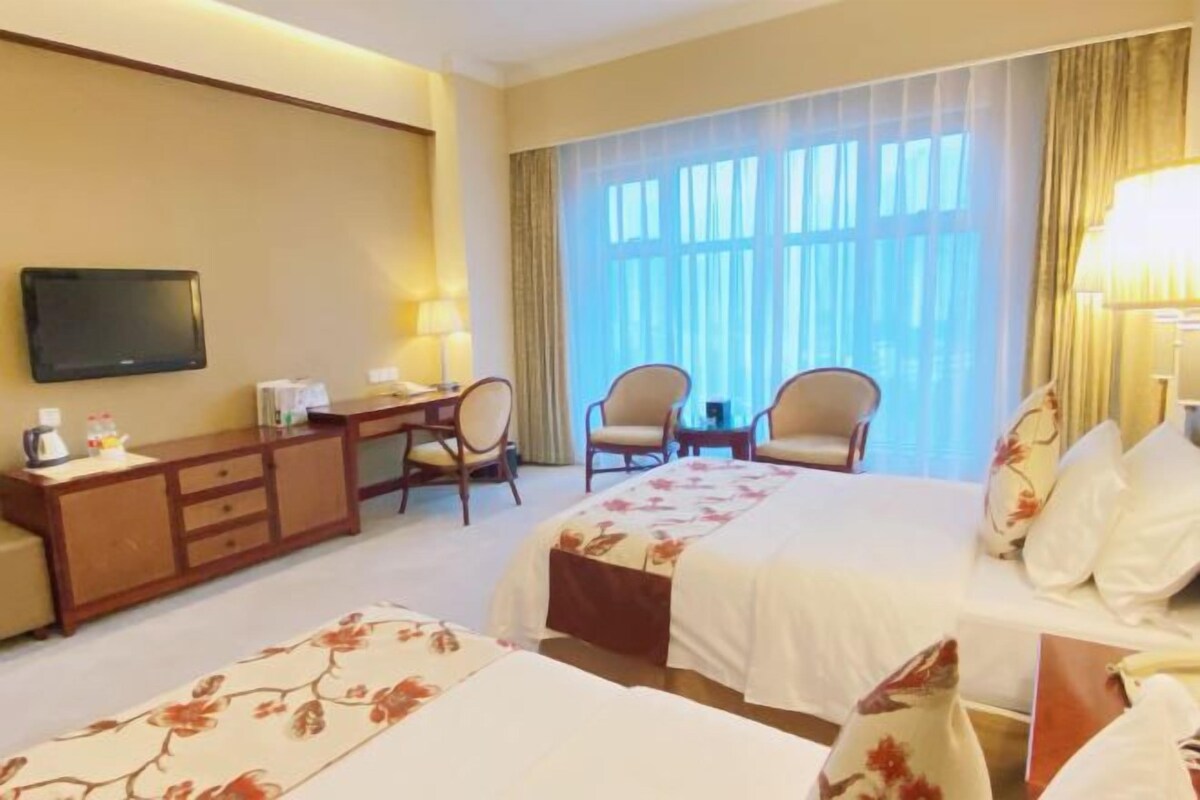A hotel room with two beds, a TV, a desk, and a chair.