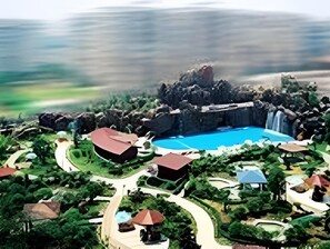 A resort with a central swimming pool, surrounded by lush greenery and various buildings. - Dolton Changsha Spa Hotel (Changsha)