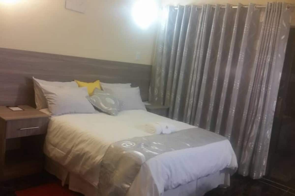 A hotel room with a bed, a nightstand, and a curtain.