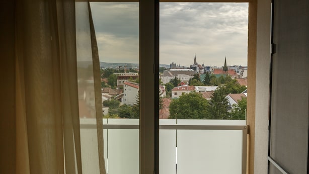 A view from a balcony with a cityscape in the background, including buildings and a church spire. - Cluj Lux Apartments Platinia (Cluj-Napoca)