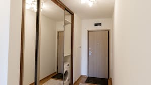 A hallway with a large mirror, a washing machine, and a door. - Cluj Lux Apartments Platinia (Cluj-Napoca)