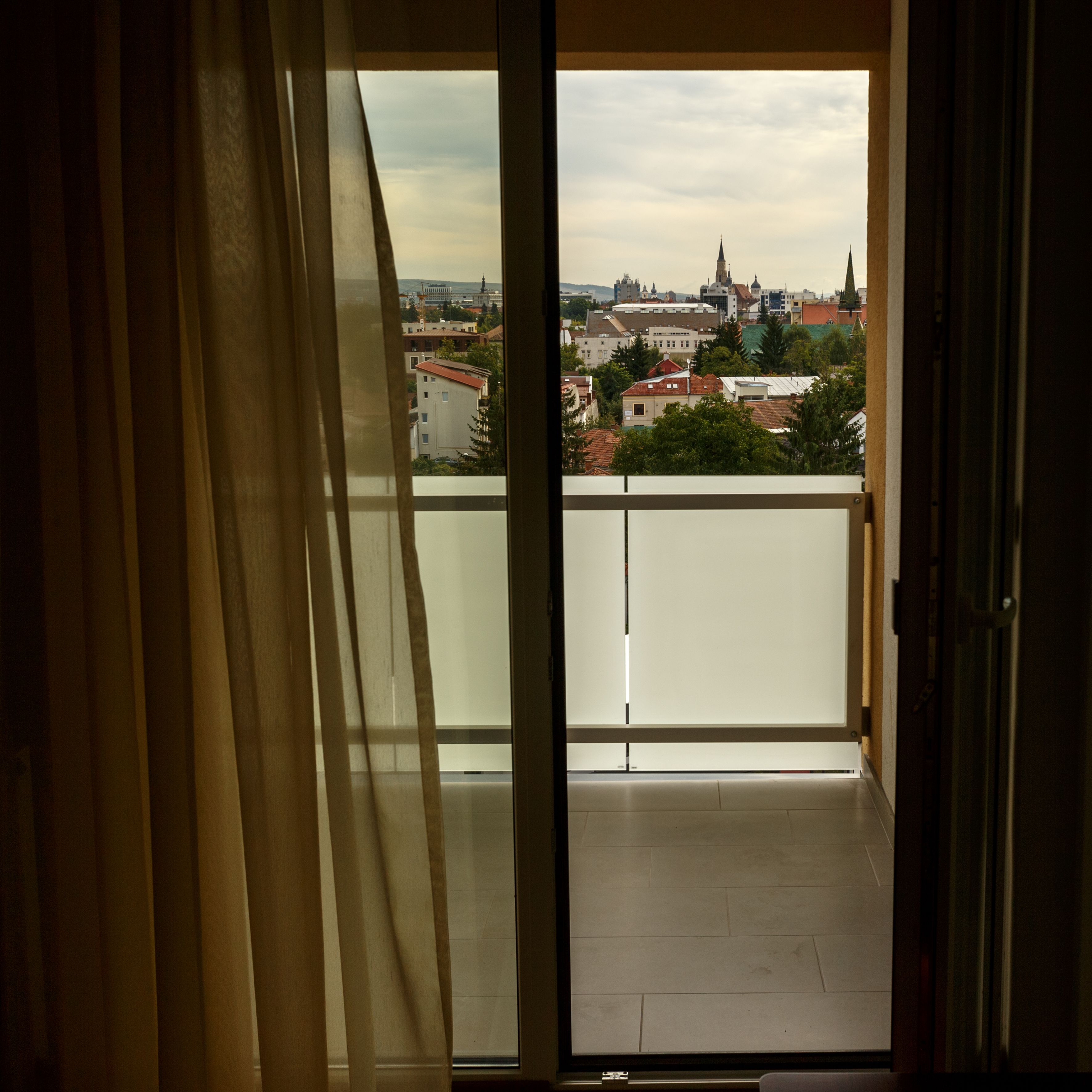 A view from a balcony with a cityscape in the background.