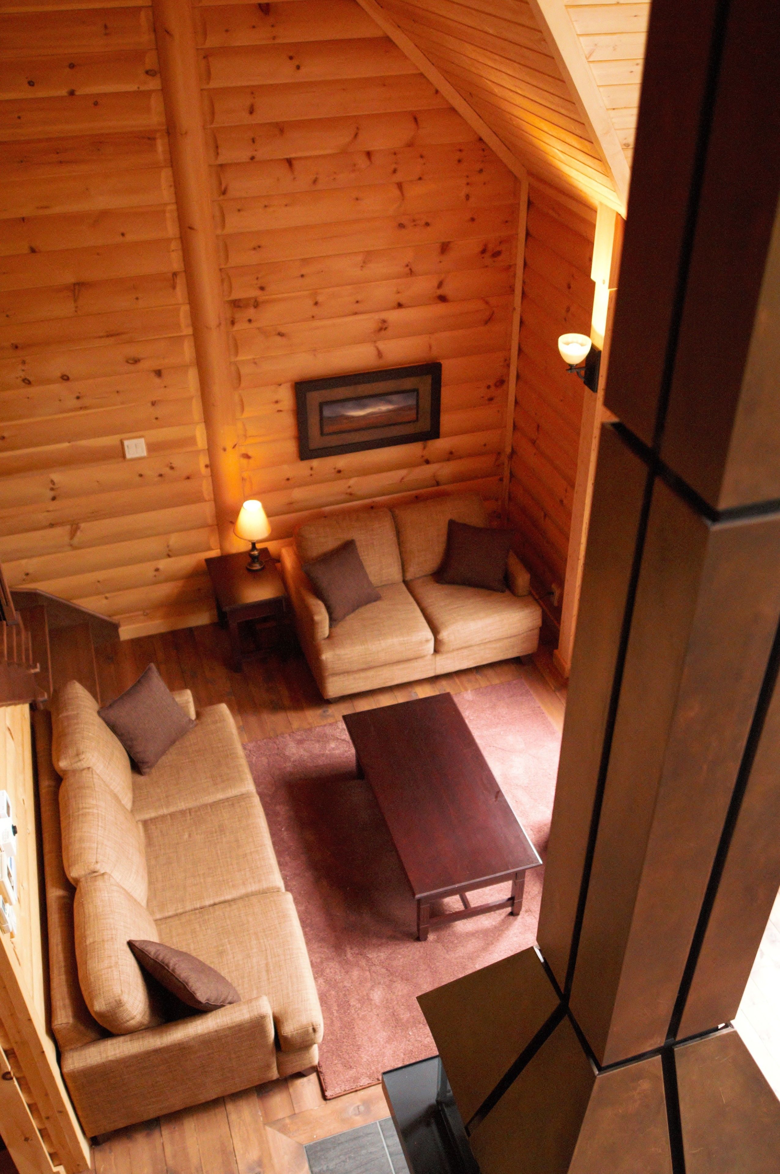 A cozy log cabin interior with a sofa set, a small table, and a framed picture on the wall.