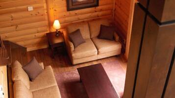 A cozy log cabin interior with a sofa set, a small table, and a framed picture on the wall.