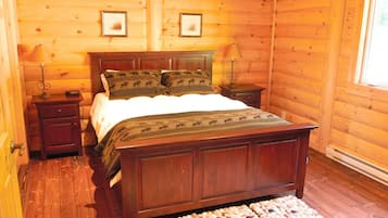 Een slaapkamer met houten lambrisering, een bed, twee nachtkastjes en twee lampen.