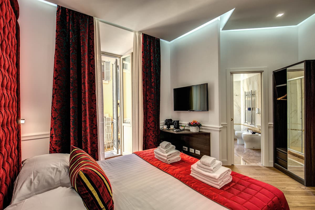 A hotel room with a bed, a TV, a bathroom, and a wardrobe.