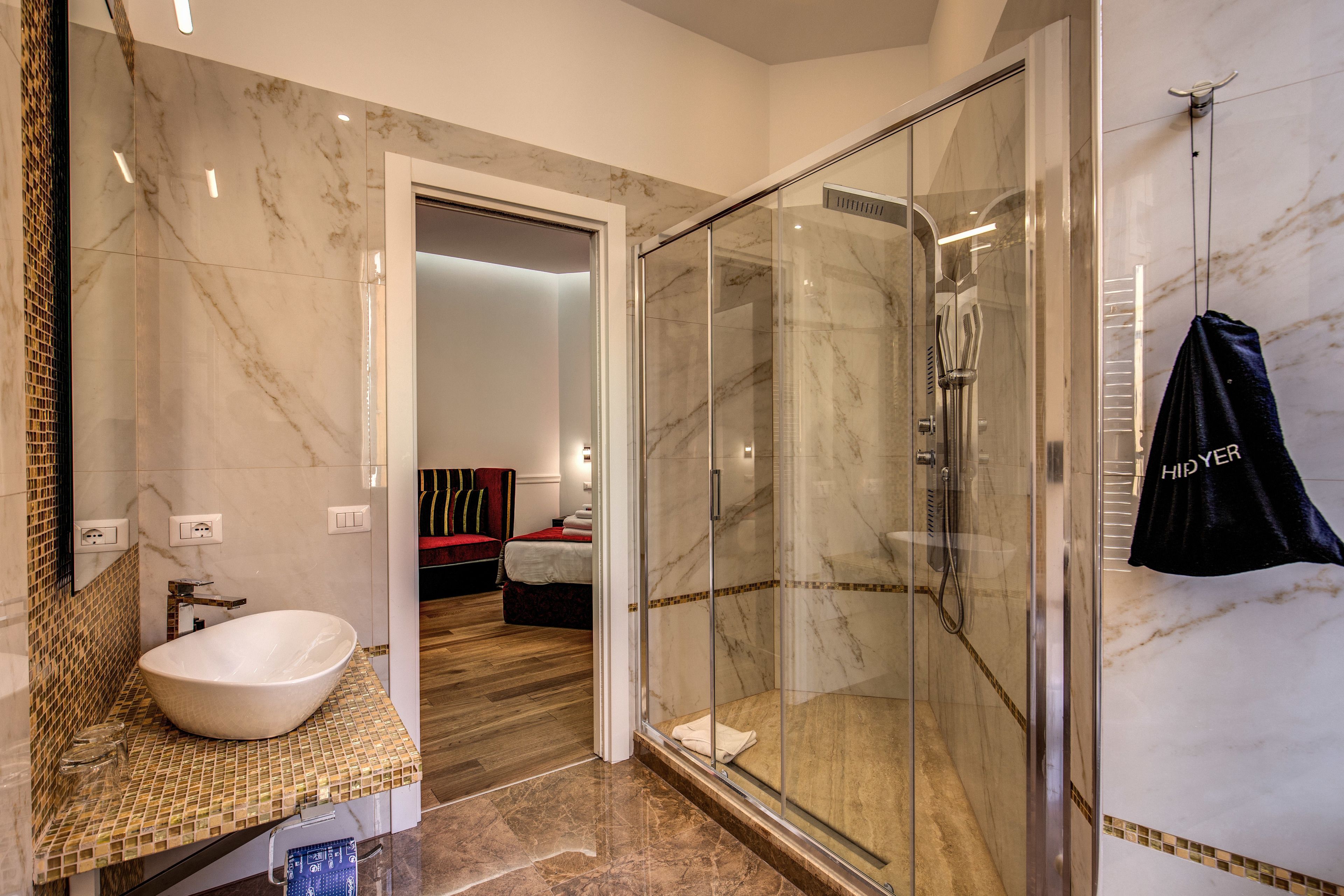 Une salle de bain moderne avec une douche à parois de verre, un lavabo recouvert de carreaux de marbre et un porte-serviettes apparent.