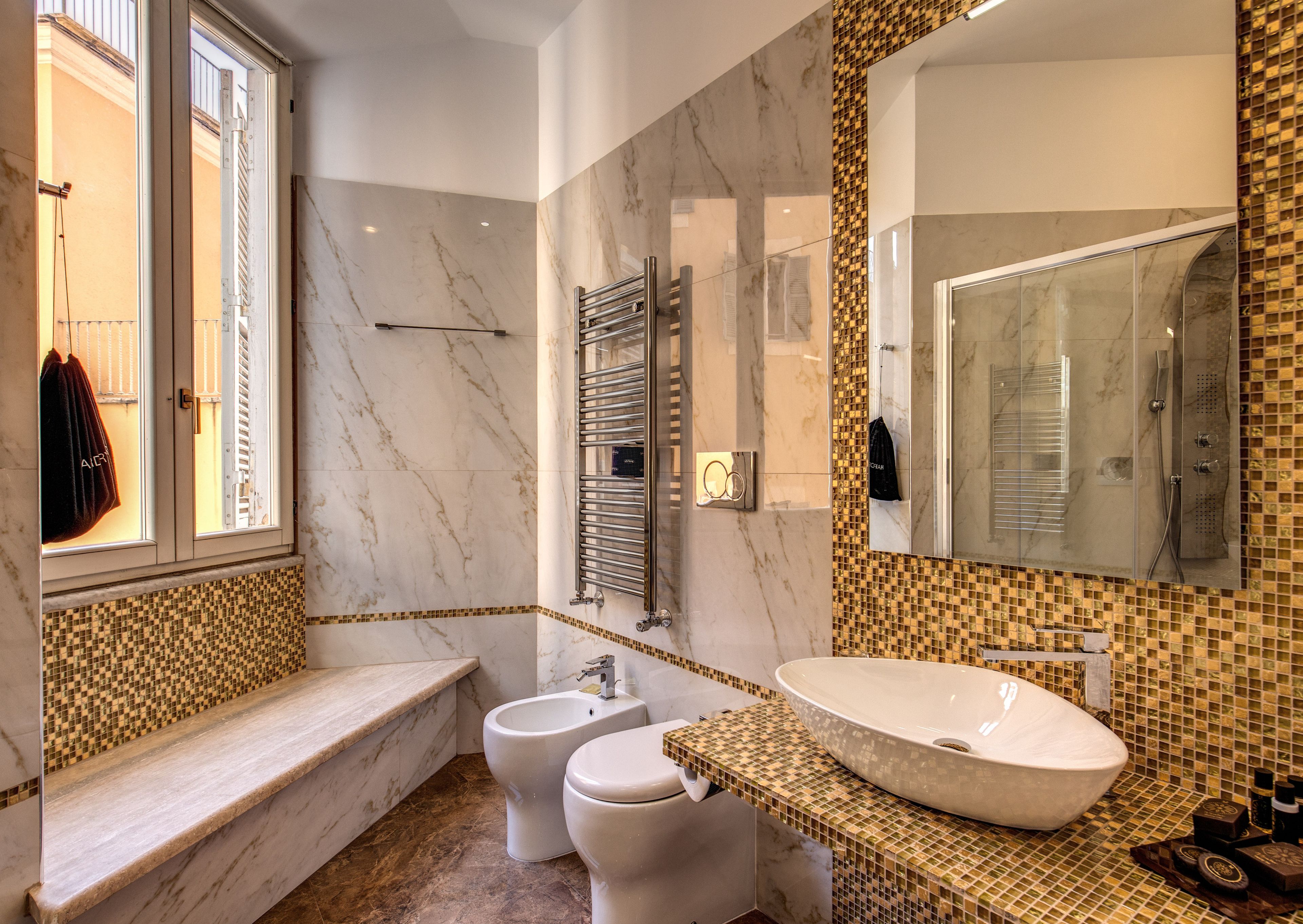 Une salle de bain moderne avec une baignoire, deux toilettes, un lavabo et un grand miroir.