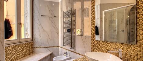 Une salle de bain moderne avec une baignoire, deux toilettes, un lavabo et un grand miroir.