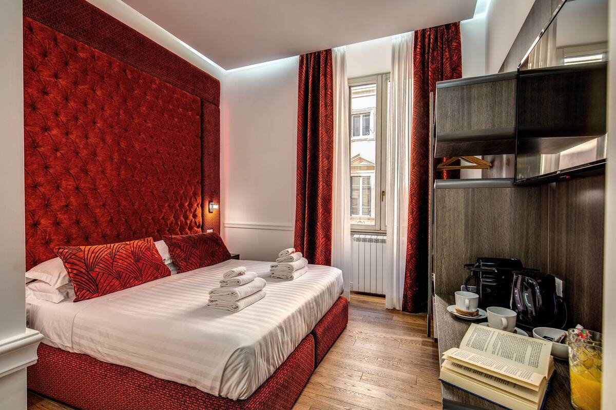 A hotel room with a large bed, a coffee machine, and a bookshelf.