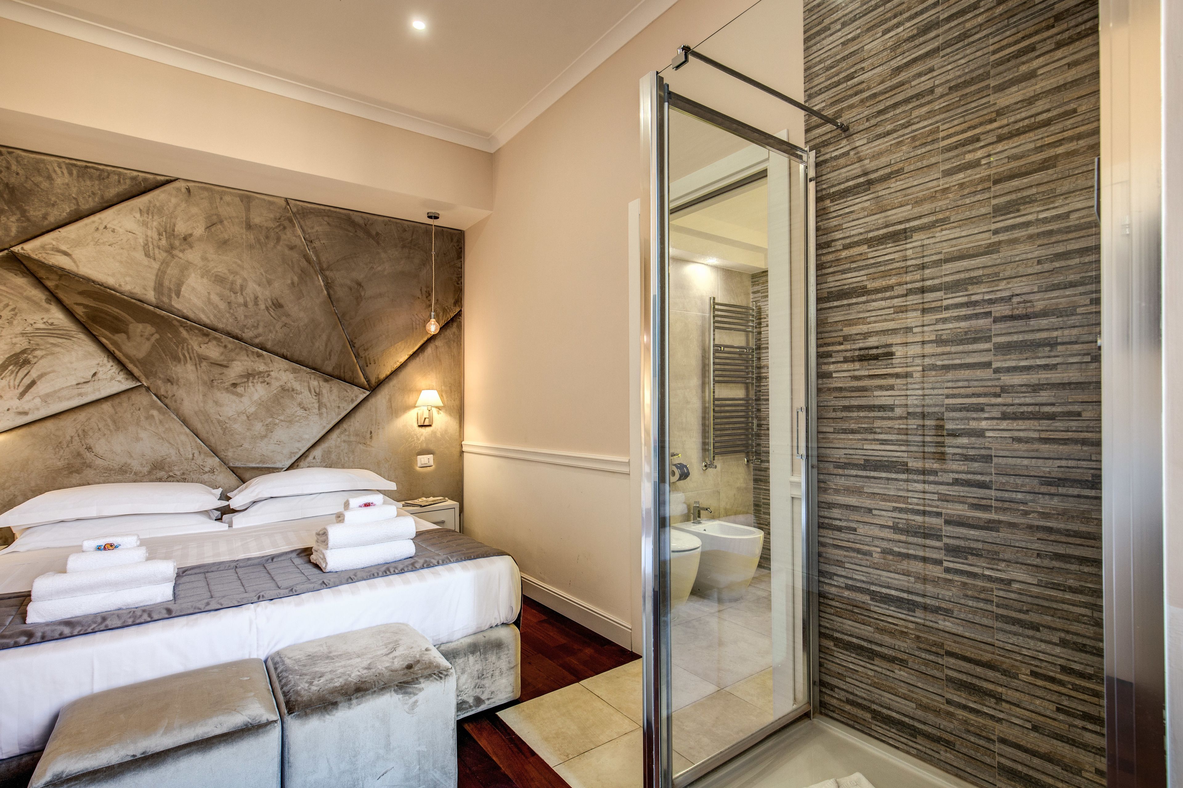 Une chambre d’hôtel moderne dotée d’un grand lit, d’une douche en verre et d’un mur à texture.