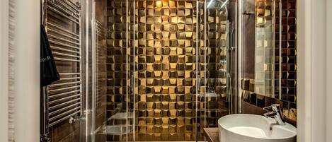 A modern bathroom with a glass-enclosed shower, two sinks, and a patterned wall.