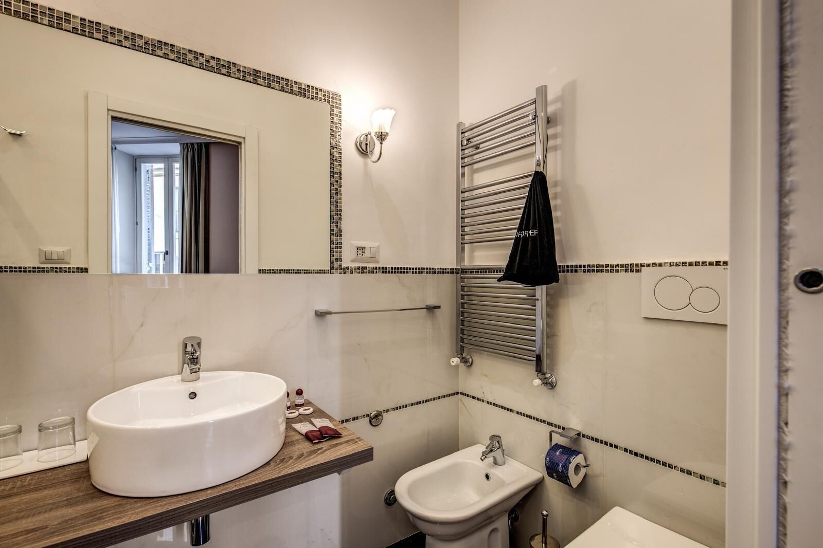 A bathroom with a large white sink, a smaller sink, a mirror, a towel rack, and a toilet.
