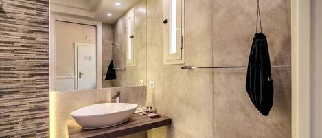 Un baño moderno con un lavamanos blanco grande, un espejo y una toalla colgada en un perchero.