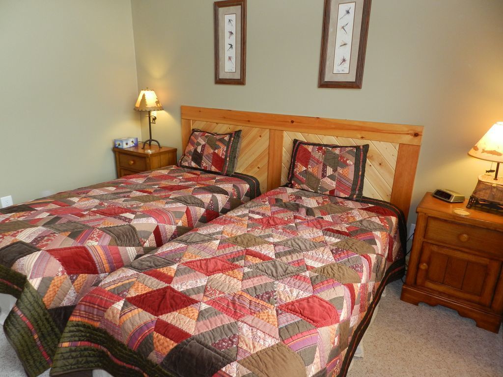 A double bed with a quilt, two bedside tables, and framed pictures on the wall.