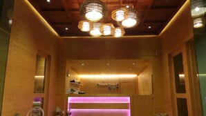 A wooden interior with a reception desk, pendant lights, and a small seating area. - Arcadia Resort (Pluak Daeng)