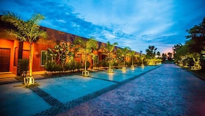 A hotel with a swimming pool, palm trees, and a pathway leading to the pool. - Arcadia Resort (Pluak Daeng)