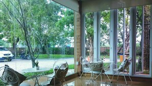 A room with large windows, a round table, and metal chairs. - Arcadia Resort (Pluak Daeng)