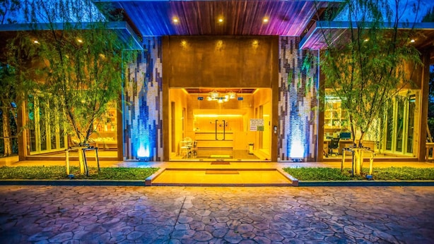 A modern hotel entrance with a stone-paved driveway leading to a reception area. - Arcadia Resort (Pluak Daeng)
