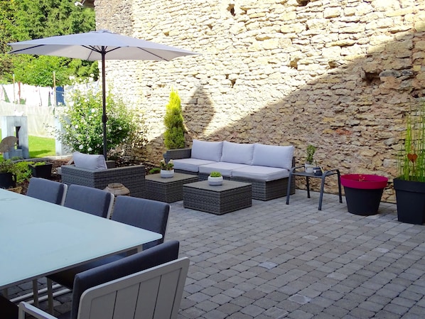 Un patio al aire libre con mobiliario de mimbre, una mesa y plantas en macetas.