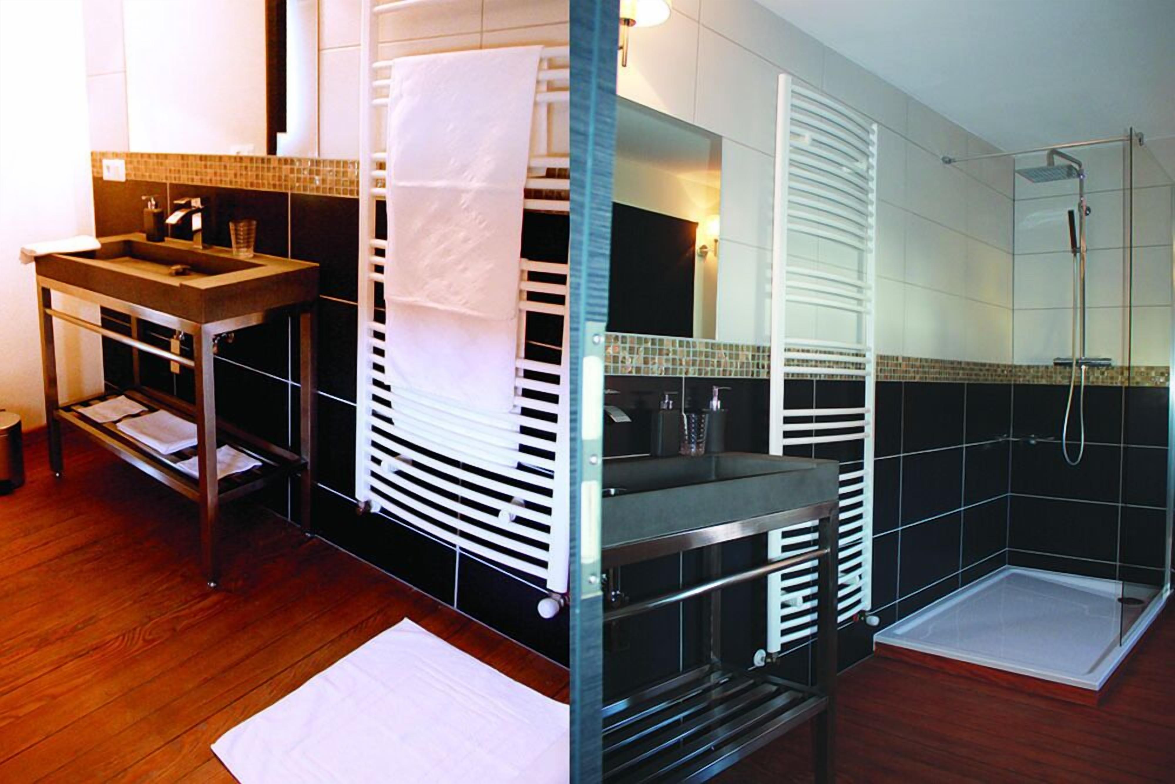 A modern bathroom with a wooden vanity, a glass shower enclosure, and a tiled backsplash.