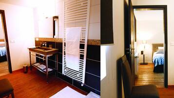 Een hotelkamer met een houten vloer, een wastafel, een spiegel, een radiator en een bed met een blauwe deken.