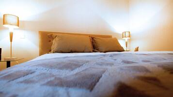 A neatly made bed with two pillows, a headboard, and two bedside lamps.