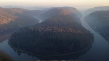 A panoramic view of a river surrounded by forested hills.