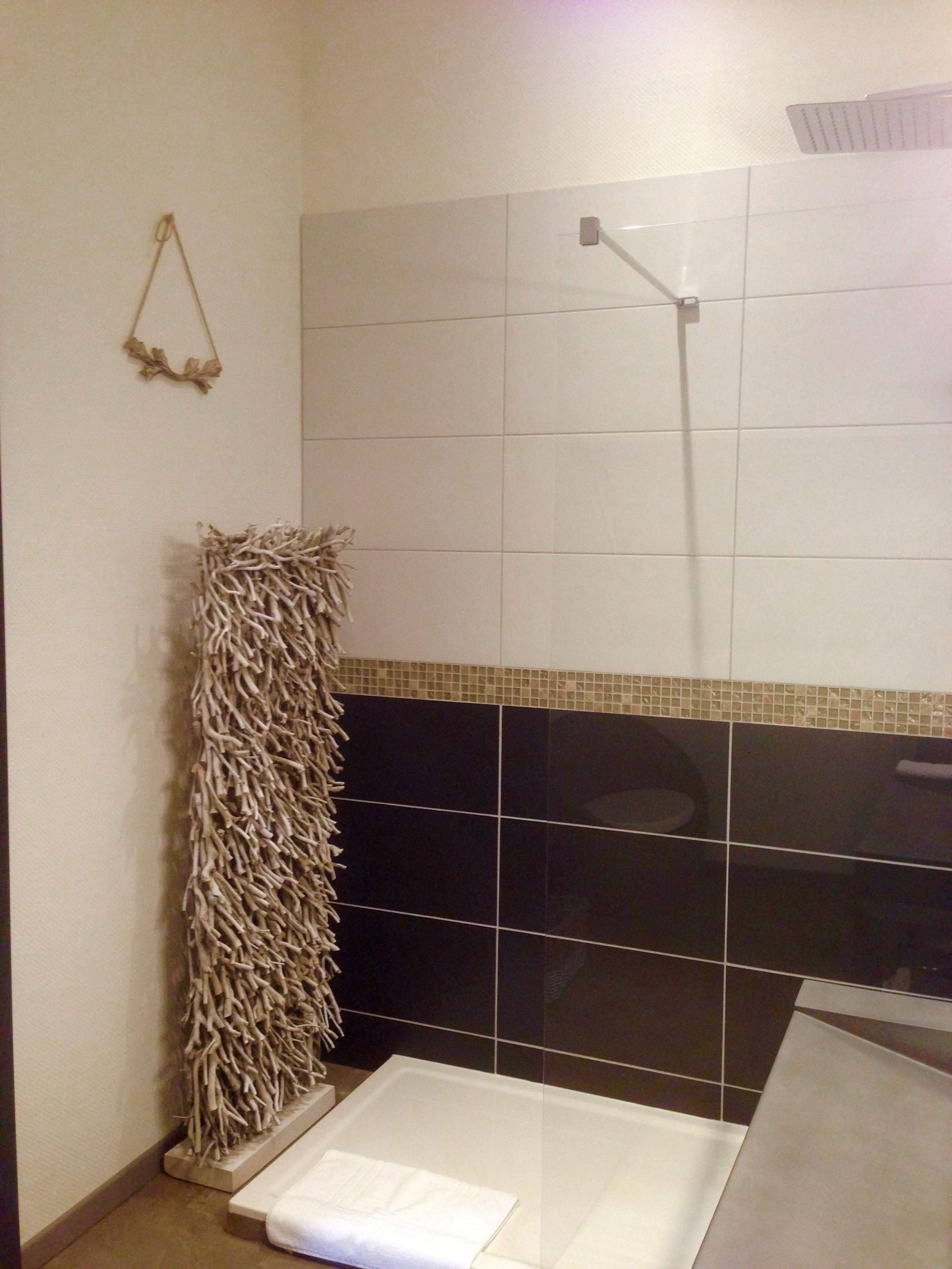 A bathroom with a shower, a towel rack, and a decorative wall piece.