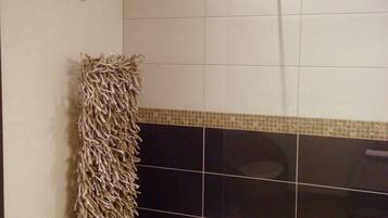 A bathroom with a shower, a towel rack, and a decorative wall piece.