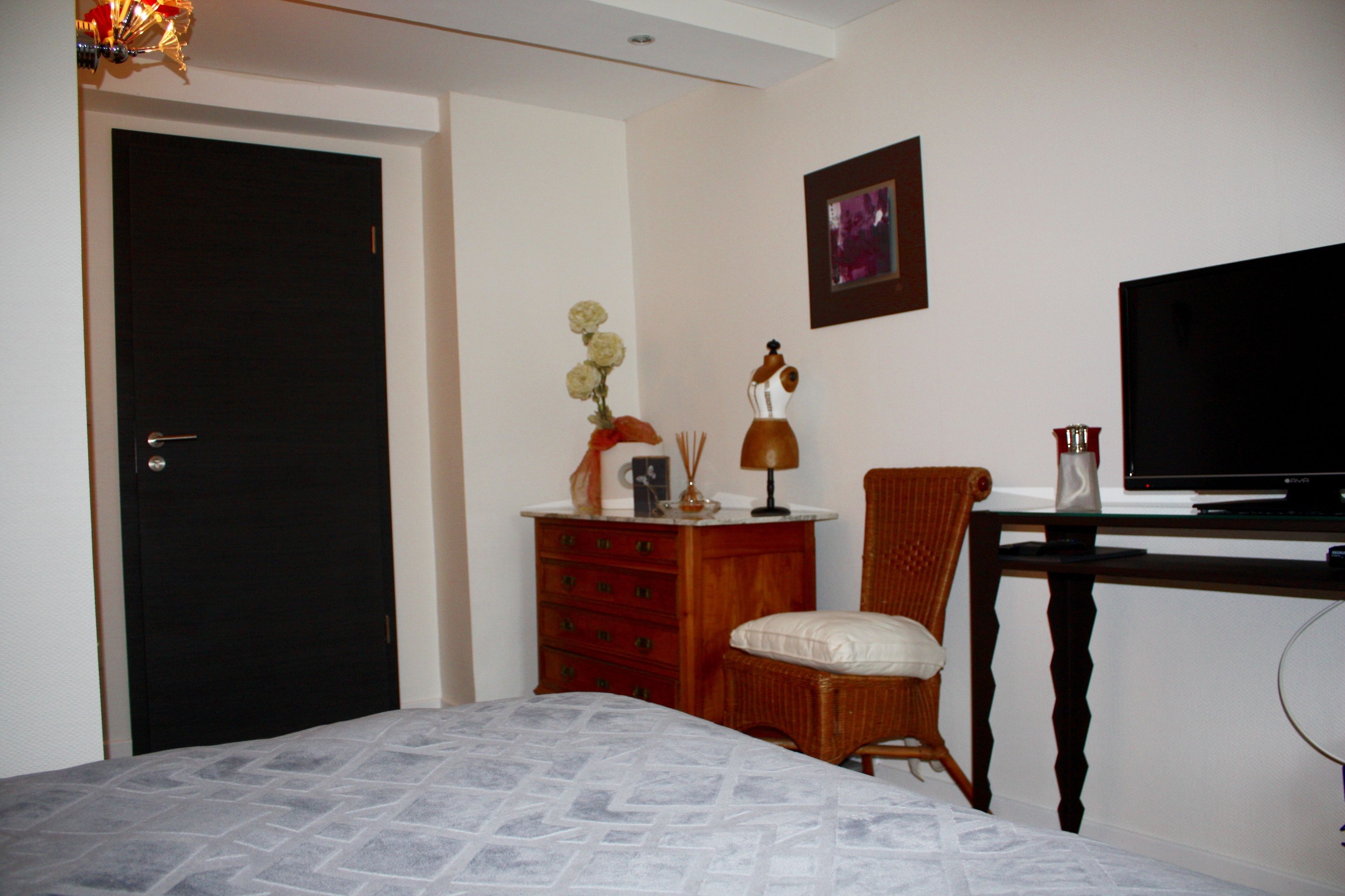 Een hotelkamer met een bed, een kaptafel, een stoel, een bureau met een televisie en een deur.