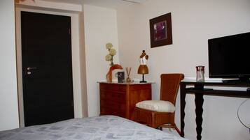 Een hotelkamer met een bed, een kaptafel, een stoel, een bureau met een televisie en een deur.