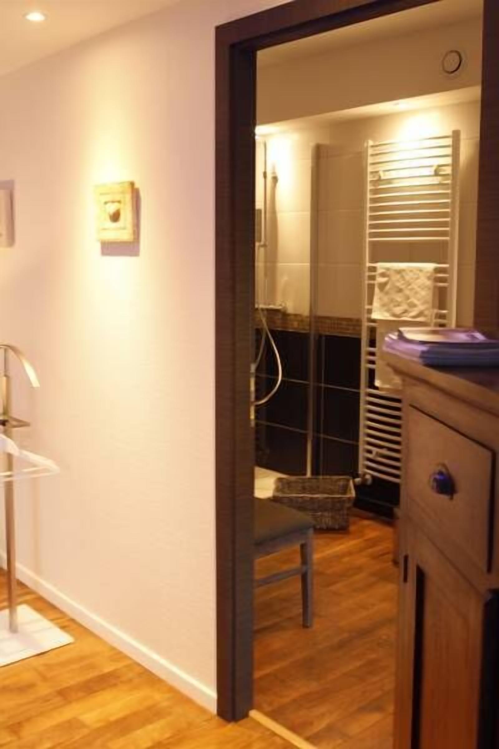 A bathroom with a wooden floor, a towel rack, and a shower area.