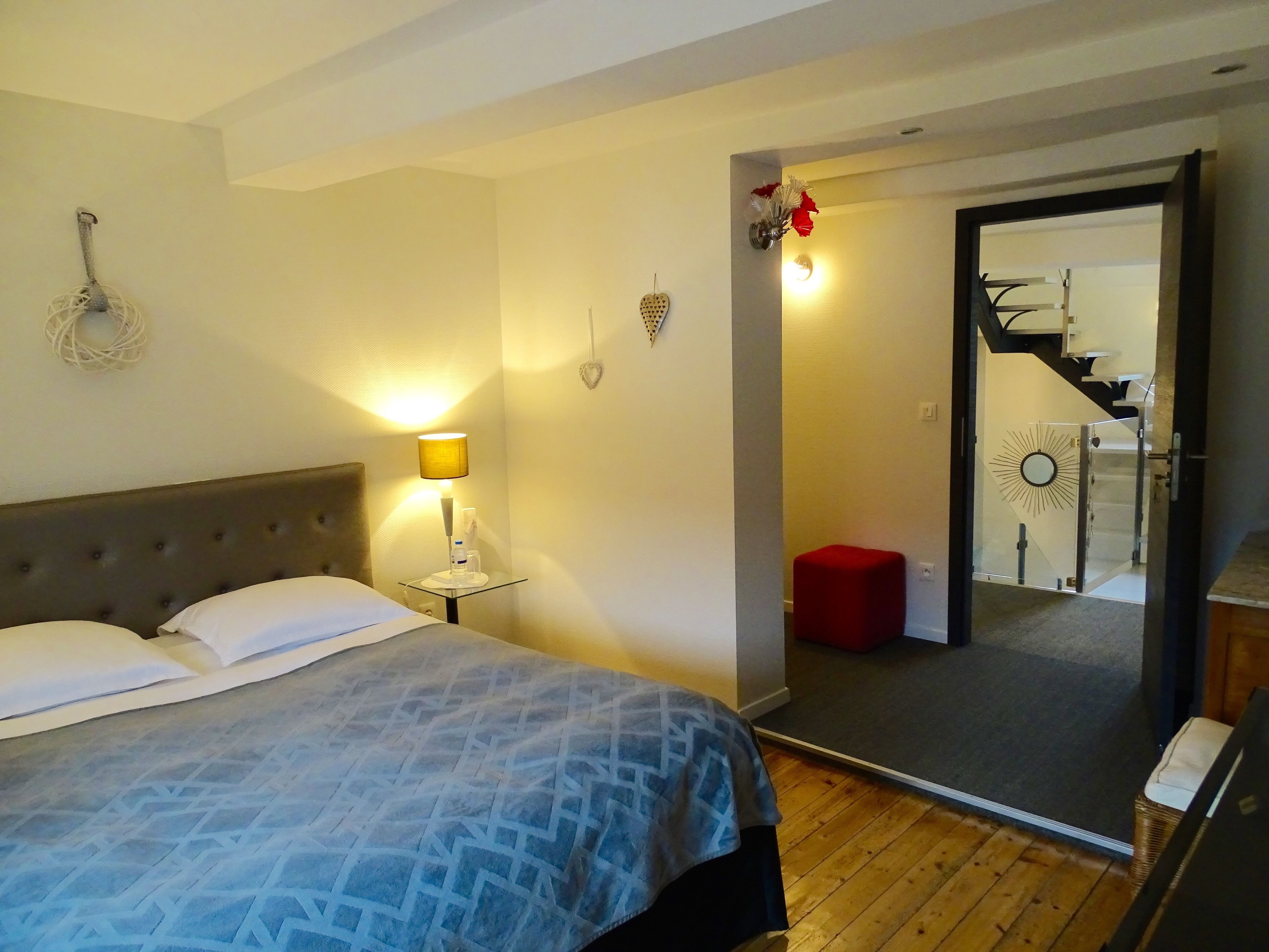 Ein Schlafzimmer mit Bett, Nachttischlampe und einem Spiegel, der eine Treppe reflektiert.