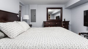 Une chambre à coucher avec un grand lit, une commode, un miroir et un téléviseur.