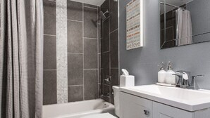 Une salle de bain moderne équipée d’une baignoire, de toilettes et d’un meuble-lavabo.