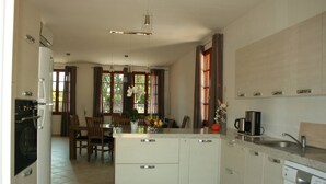 A modern kitchen with a central island, a dining area with a table and chairs, and a built-in oven. - House / Villa - Port-Vecchio (Porto-Vecchio)