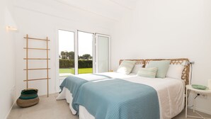 Une chambre avec deux lits, une fenêtre donnant sur un paysage verdoyant, une échelle et un panier en osier.