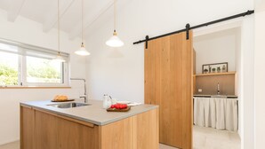 Une cuisine moderne dotée d’un îlot central, de meubles en bois et de luminaires suspendus.