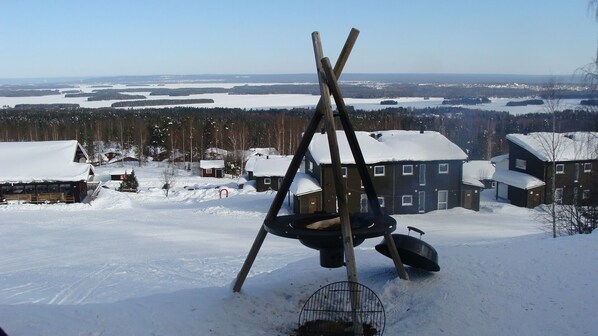 A snowy landscape with a swing set in the foreground, houses in the background, and a clear view of the surrounding area.