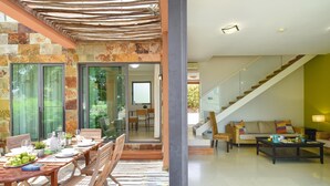 A modern living area with a dining table set for four, a sofa, and a staircase. - Salobre Golf Lagos 40 by VillaGranCanaria (San Bartolomé de Tirajana)