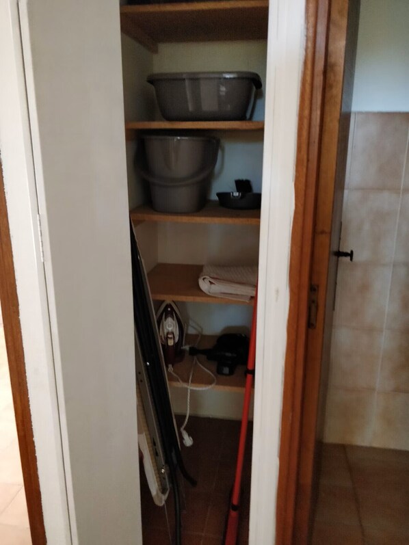A kitchen with shelves, a sink, and a broom.