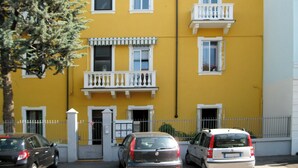 A yellow building with multiple windows and balconies, a gated entrance, and parked cars in front. - House Kloss - cozy apartment nouveau (verona)