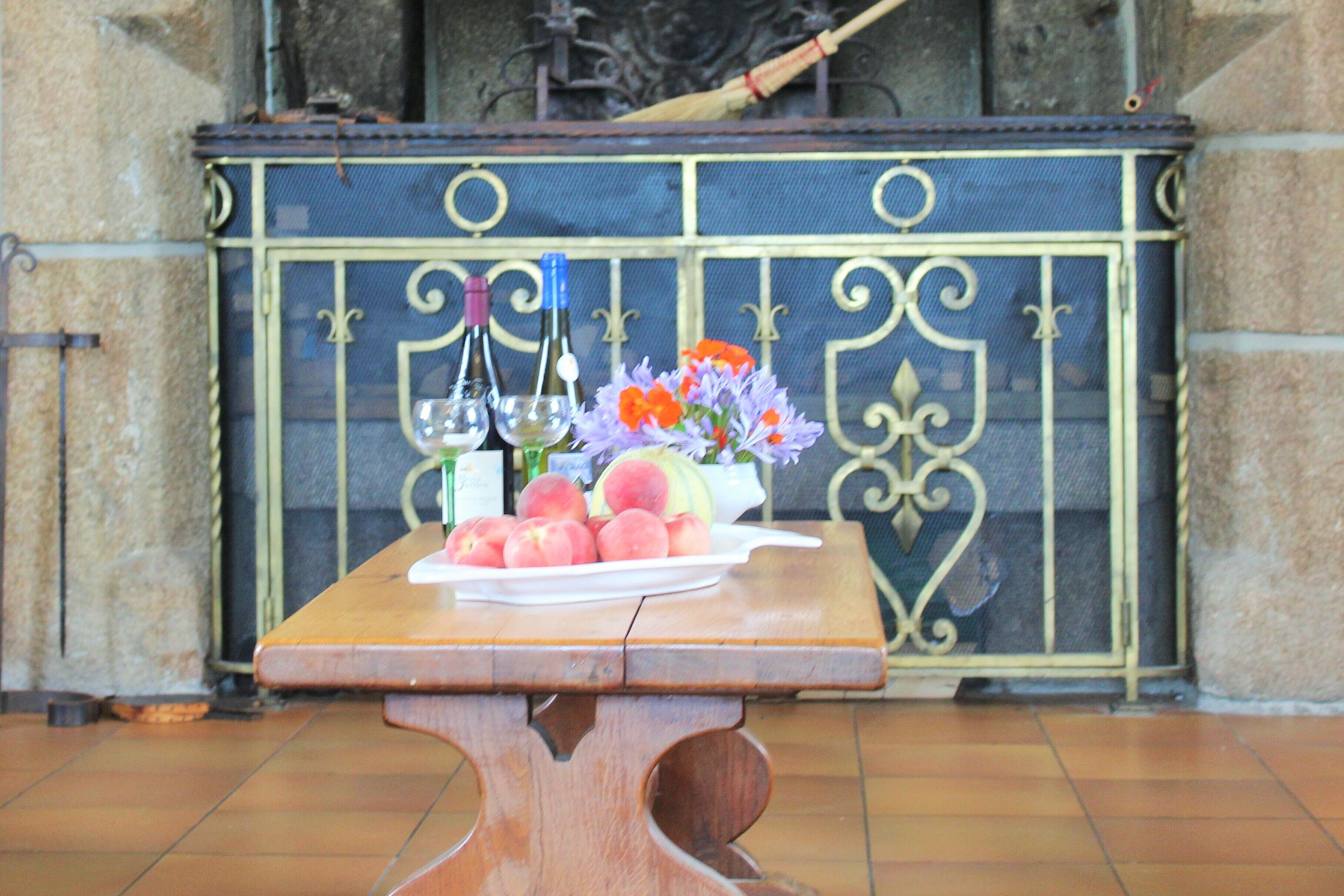 A table with a plate of fruit and bottles, set against a decorative metal screen.