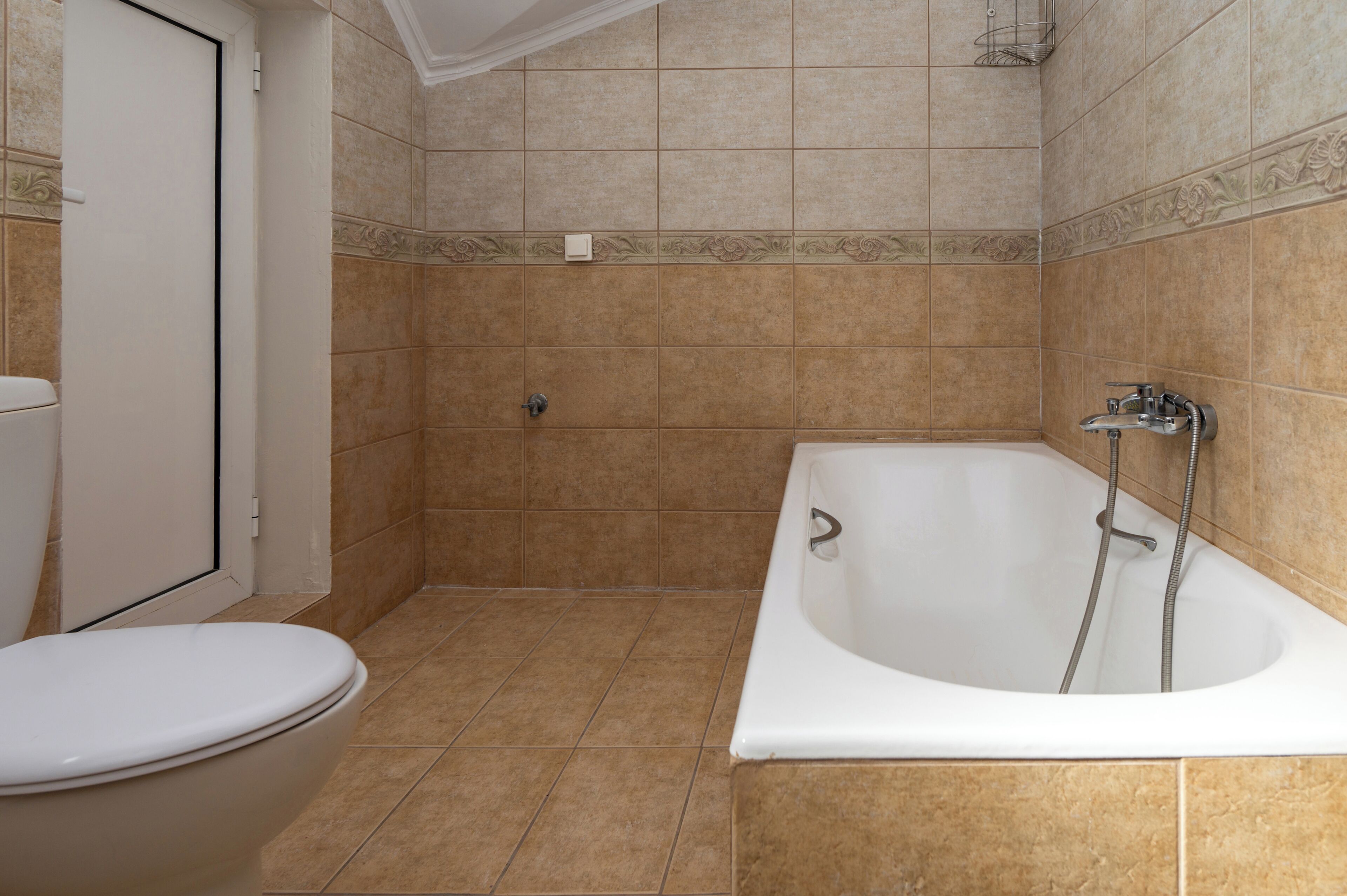 A bathroom with a toilet, a bathtub, and tiled walls.