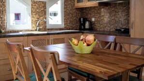 Eine Küche mit Holzschränken, eine grüne Schüssel mit Zwiebeln auf dem Tisch und ein Fenster mit Blick.