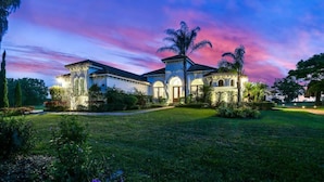 A large, two-story house with a well-maintained lawn and a palm tree in the front yard.